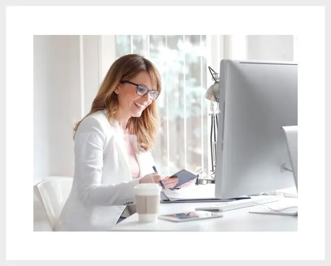 A woman sitting at her desk writing on paper.