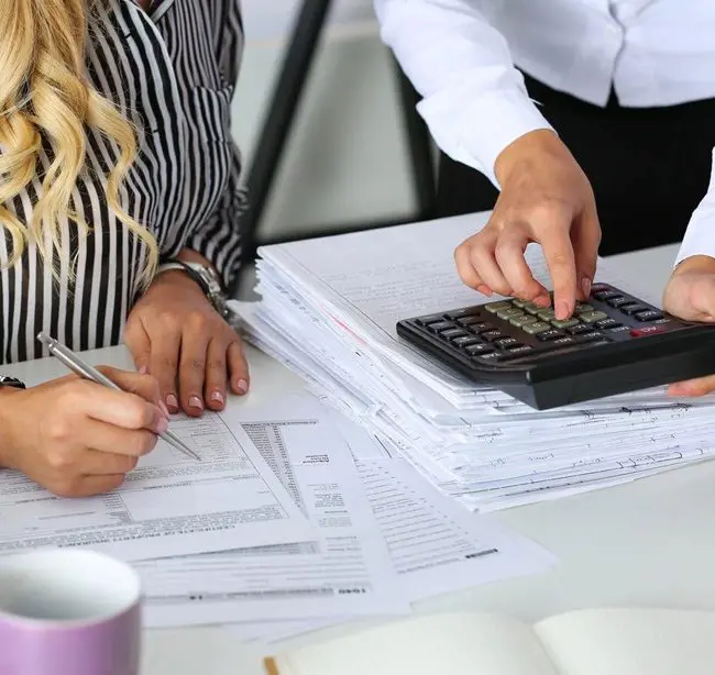 A couple of people sitting at a table with papers.